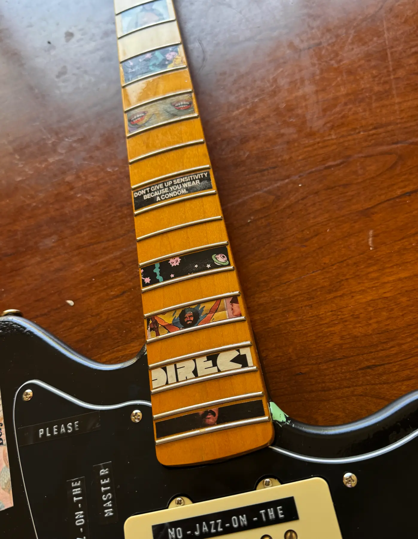 Close-up of miniature collage pieces applied between the guitar frets