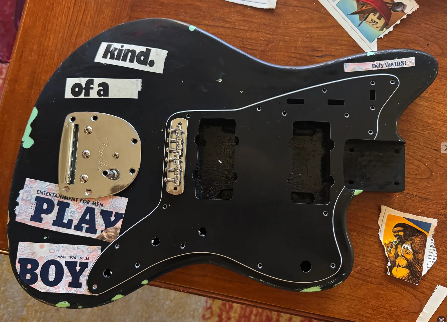Disassembled black guitar body with collage elements being positioned
